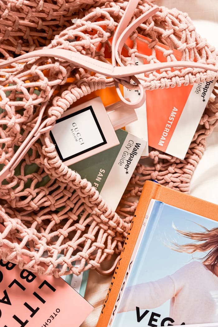 Stylish flat lay with travel guides, net bag, and luxury perfume bottle, perfect for lifestyle inspiration.